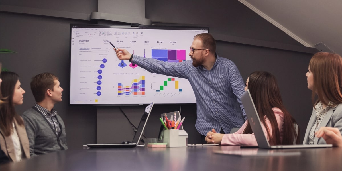 Business consultant presenting BI insights on a large screen to a team