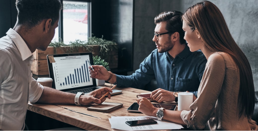 Business professionals analyzing CRM performance metrics on a laptop in a strategy meeting