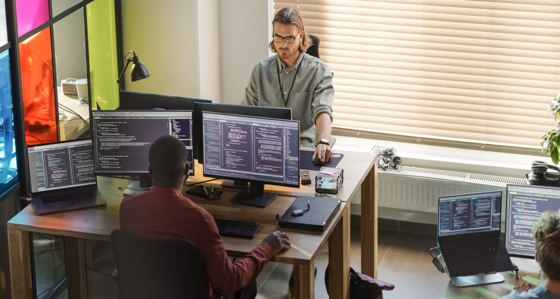 Developers working in a modern workspace, coding SaaS applications on multiple screens