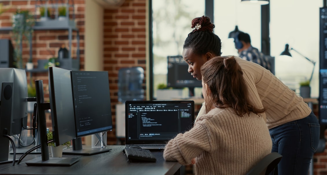 Two software developers collaborating on coding an MVP application in an open workspace