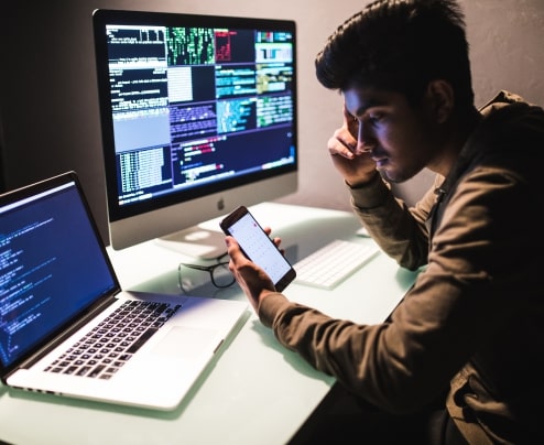 Software engineer designing and testing a mobile application prototype on a computer