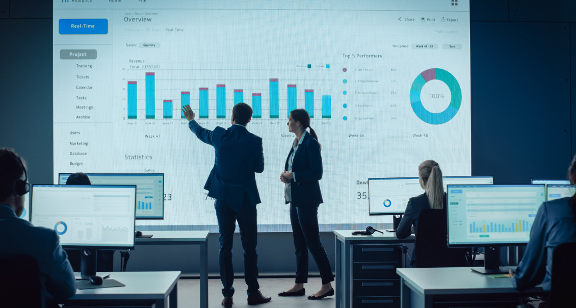 Business professionals presenting enterprise analytics and performance insights on a large screen