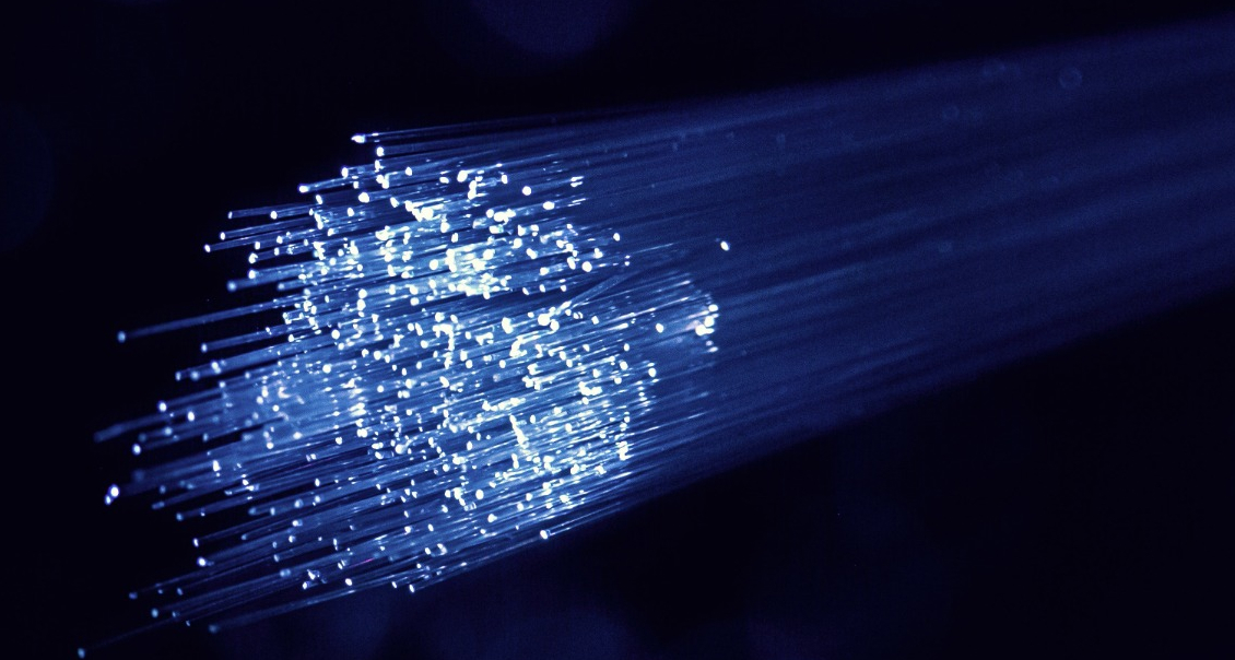 Close-up of fiber optic cables glowing with blue light, representing high-speed data transmission