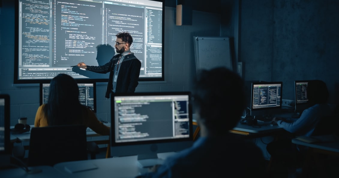 Instructor presenting code on a screen to a classroom of developers in a training session