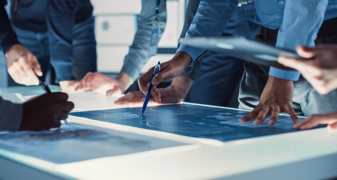 Business professionals collaborating on a digital blueprint using an interactive touchscreen