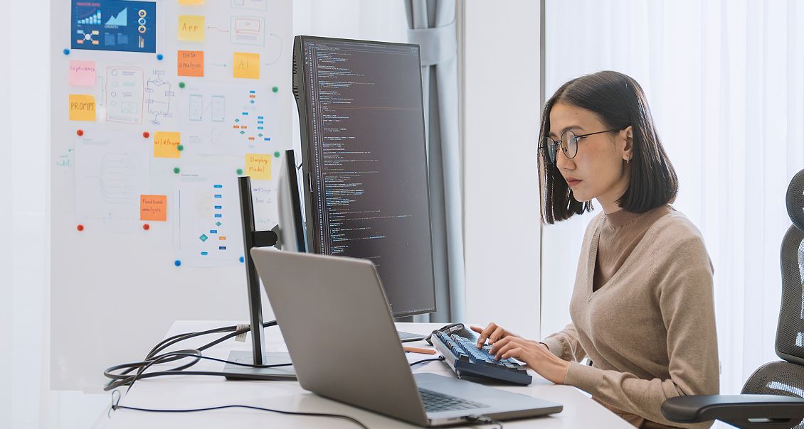 Female developer coding chatbot functionality on laptop in modern, well-lit workspace