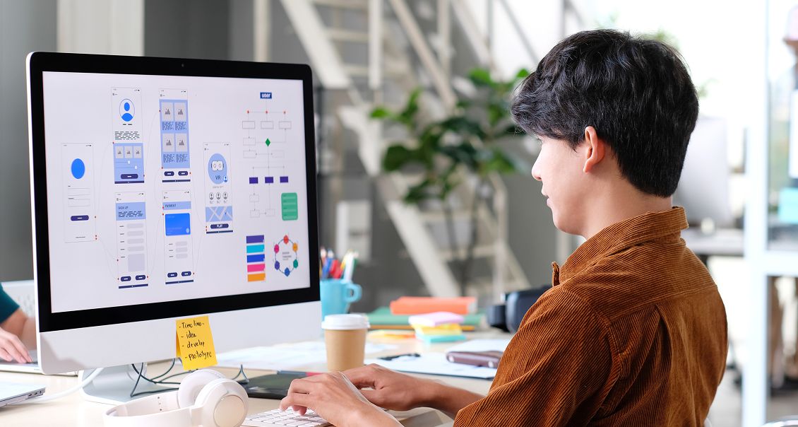 UX designer working on chatbot interface layout using data dashboards on a large monitor