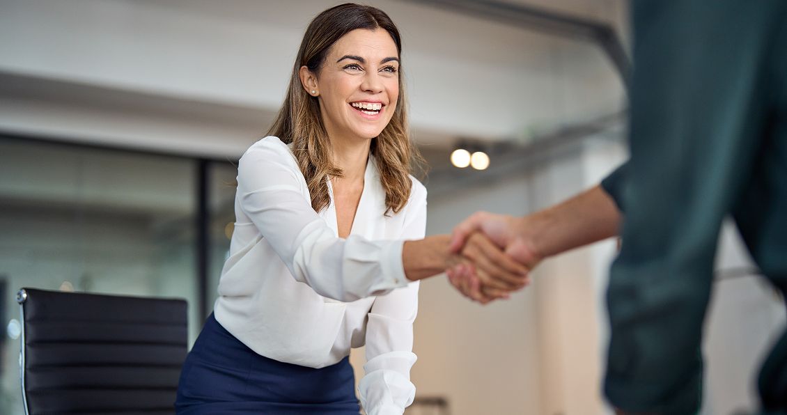 Smiling businesswoman shaking hands with a client, sealing an agreement