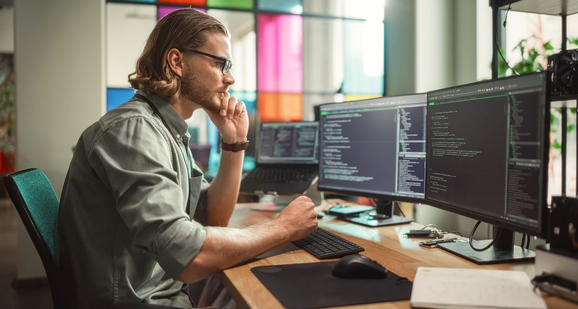 Java developer working on dual monitors in an office