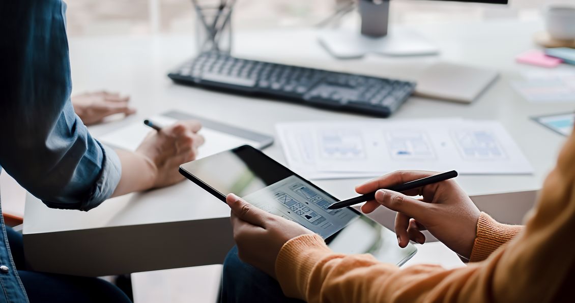 Two professionals collaborating on a tablet in an office