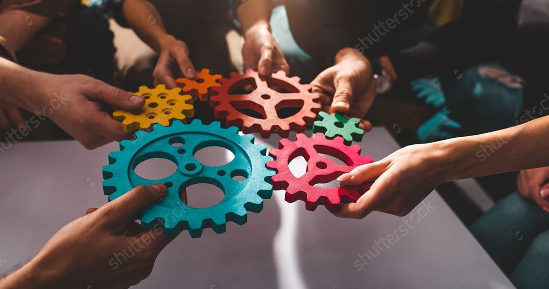 Teamwork concept: hands connecting colorful cogwheels