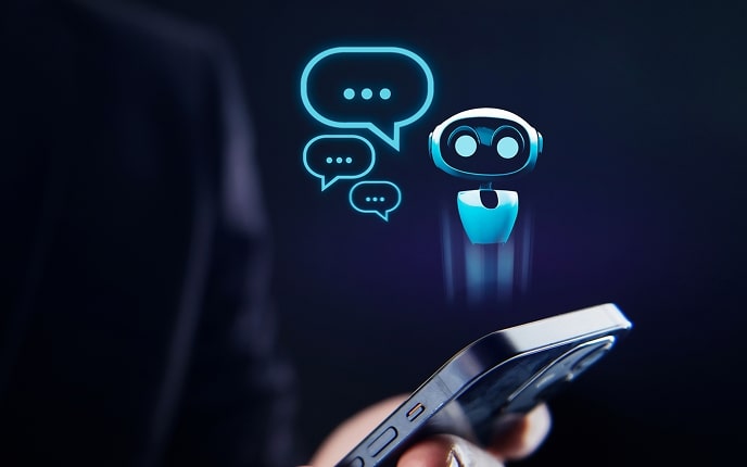A person holds a smartphone in the foreground, while a digital illustration of a chatbot robot and three speech bubble icons appear holographically above the phone against a dark background, symbolizing AI-powered conversation or virtual assistance.