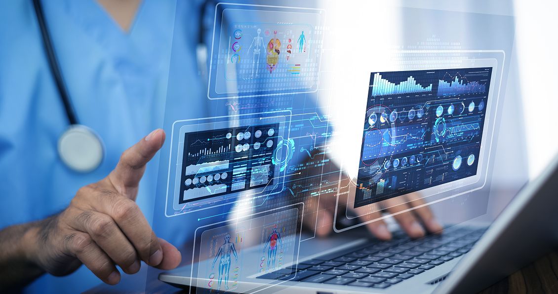 A person in blue scrubs, wearing a stethoscope, interacts with a laptop displaying various digital health data charts and medical dashboards. Transparent virtual screens show graphs, patient information, and anatomical images, suggesting advanced medical technology.