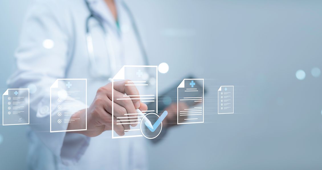 A doctor in a white coat with a stethoscope uses a touchscreen interface, interacting with floating digital medical documents and a large blue checkmark icon, symbolizing approval or validation of medical records. The background is blurred and clinical.