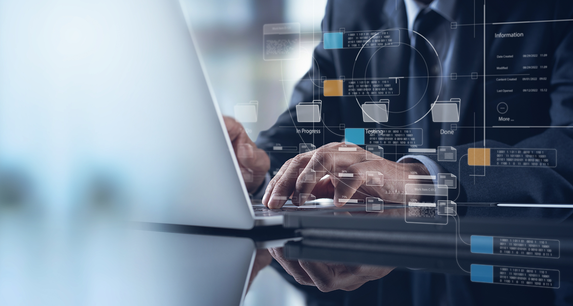 A person in a dark suit types on a laptop at a glossy desk. Overlaid digital graphics show file folders, data charts, and flow diagrams, suggesting concepts of data management, digital workflow, or cybersecurity in a modern office environment.