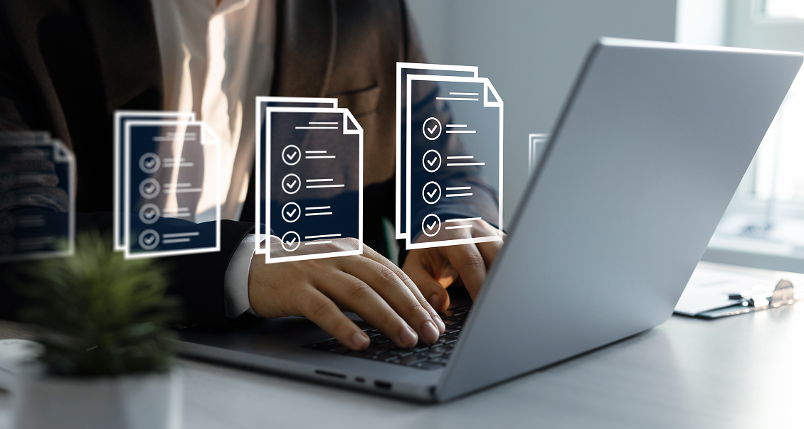 A person in a suit types on a laptop at a desk. Overlaid graphics of documents with checkmarks appear above the keyboard, symbolizing digital forms or completed tasks. There is a plant in the foreground and soft light from a window in the background.