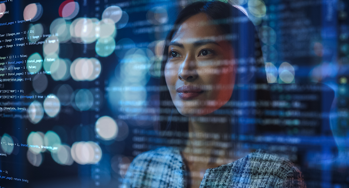 A woman gazes thoughtfully through a glass screen displaying lines of computer code. Reflections of city lights and code are seen on the glass, blending technology with her focused expression in a modern, tech-driven environment.