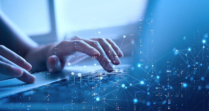 A close-up of hands typing on a laptop keyboard, overlaid with a digital network graphic of connected nodes and lines, symbolizing technology, data, and communication. The image has a blue, futuristic tone and a blurred background.