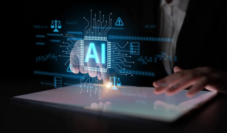 A person interacts with a touchscreen tablet, while a glowing holographic circuit board with the letters AI is projected above it, symbolizing artificial intelligence technology and digital innovation in a dark environment.