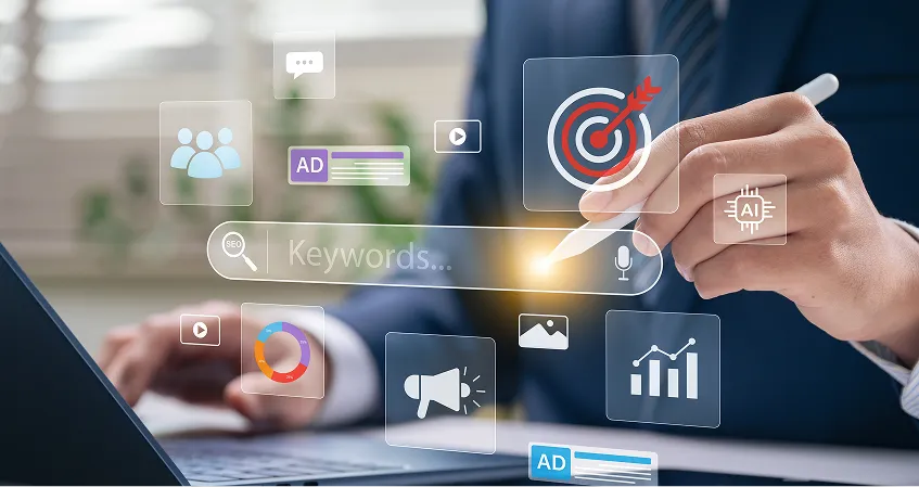 A person in a suit works on a laptop, using a stylus to interact with floating digital icons showing marketing concepts like keywords, ads, statistics, target, people, megaphone, and charts, symbolizing digital marketing and data analysis.