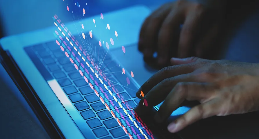 A close-up of hands typing on a laptop keyboard, with colorful digital dots and lines superimposed, symbolizing data transfer or digital communication in a blue-lit environment.