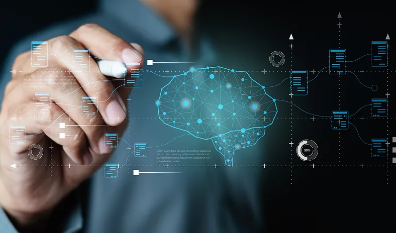 A person’s hand holds a white marker, pointing toward a digital brain graphic with network connections and data icons, representing artificial intelligence or machine learning concepts on a dark background with technical schematics.