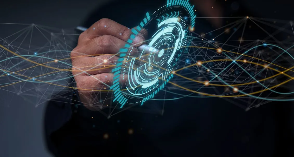 A hand interacts with a glowing, futuristic digital interface displaying concentric circles and data patterns. Abstract lines and nodes connect across the image, suggesting advanced technology, networking, or virtual reality. The background is dark.