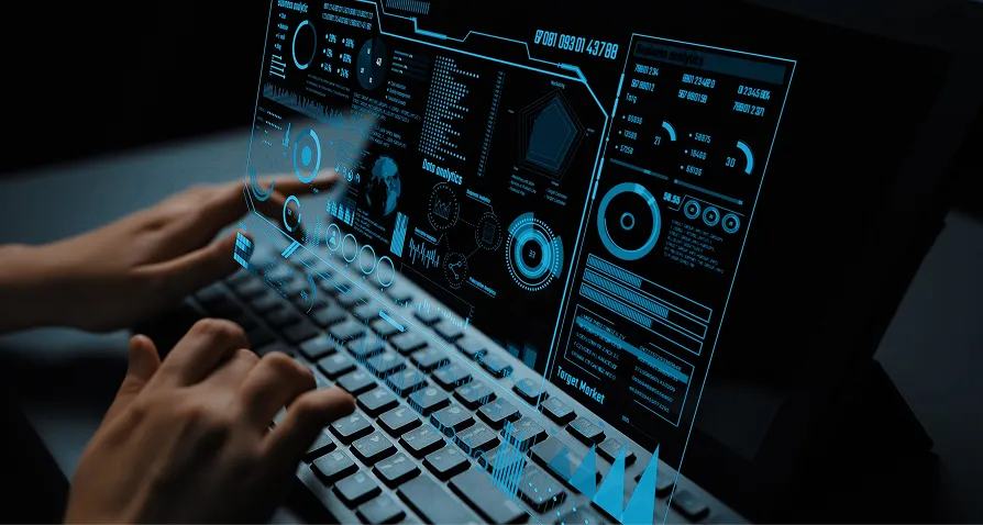 A person types on a keyboard in a dark setting. A transparent, blue-tinted virtual interface with charts, graphs, and data visualizations appears above the keyboard and screen, suggesting advanced technology or data analysis activities.