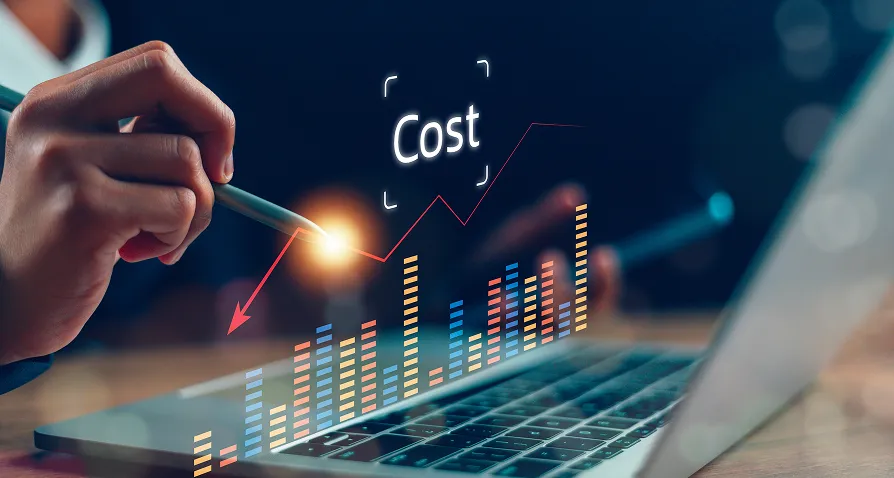 A hand holding a pen points at a glowing spot near a rising bar chart on a laptop screen. The word Cost is centered above the chart, with red and orange upward-trending lines, symbolizing increasing costs or financial analysis.