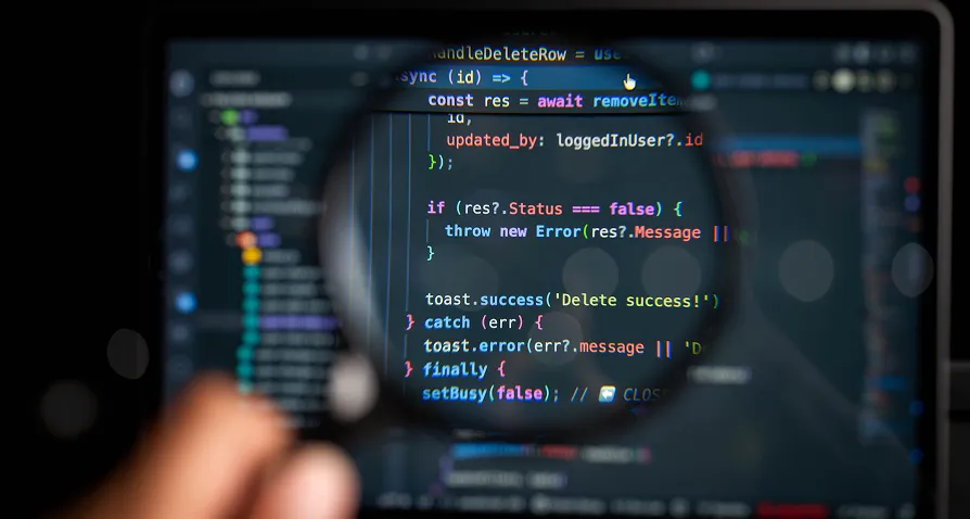 A magnifying glass held over a computer screen highlights colorful code in a text editor. The code uses JavaScript syntax and focuses on error handling and status checks. Blurred background shows more code and developer tools.